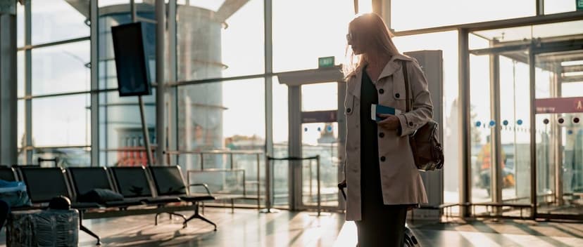A woman walking into an airport with her passport.