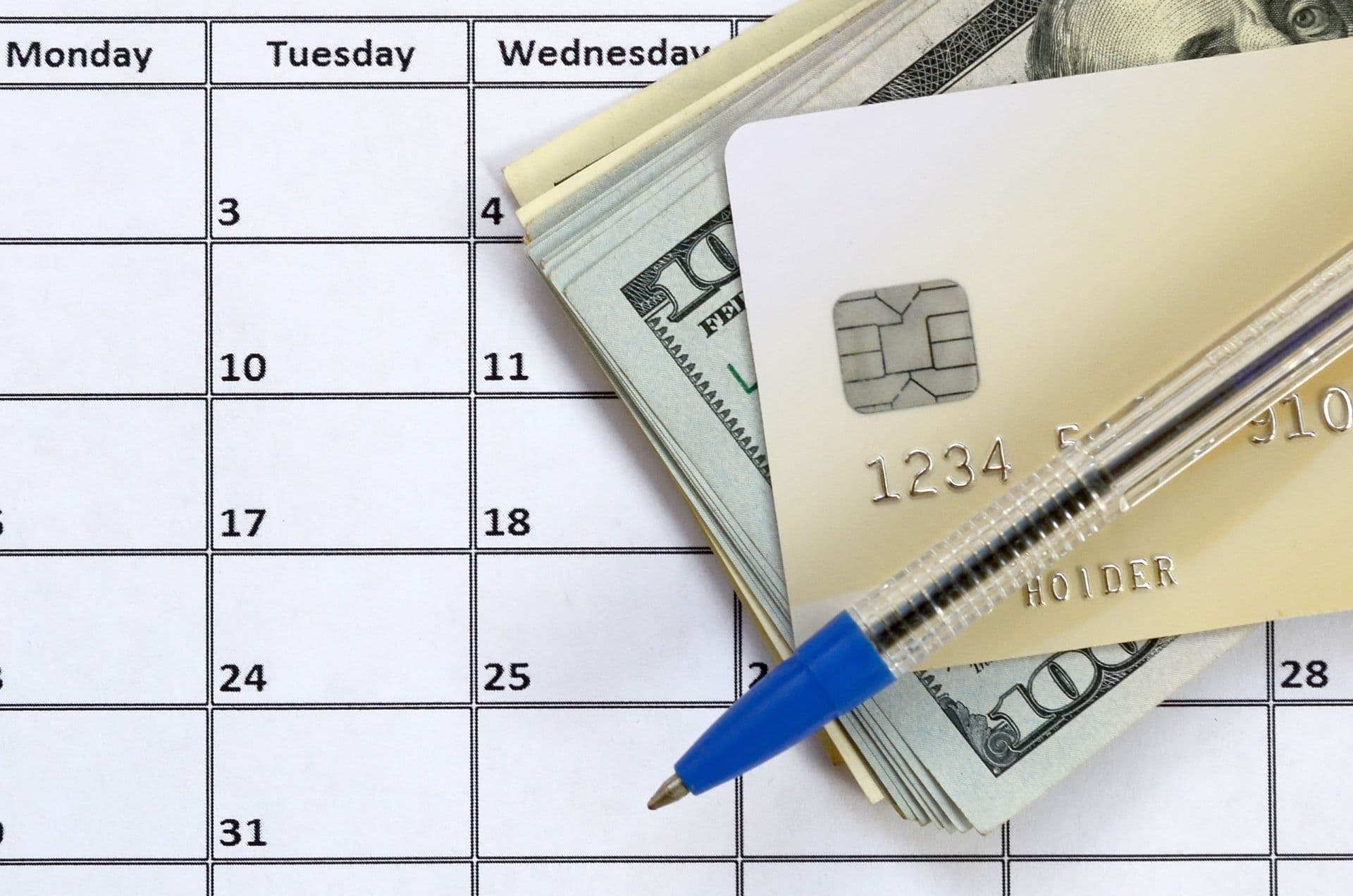 A credit card and money on top of a calendar