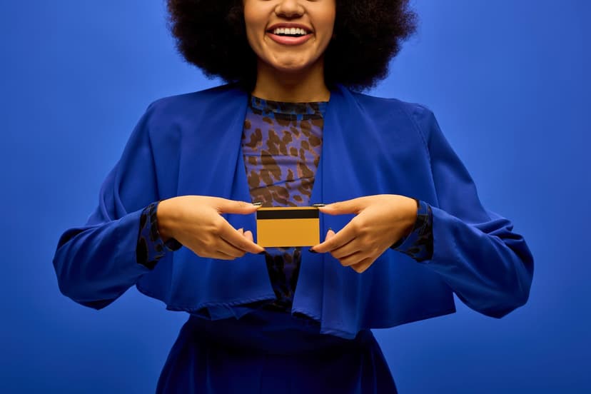 A woman in blue holds up a gold credit card